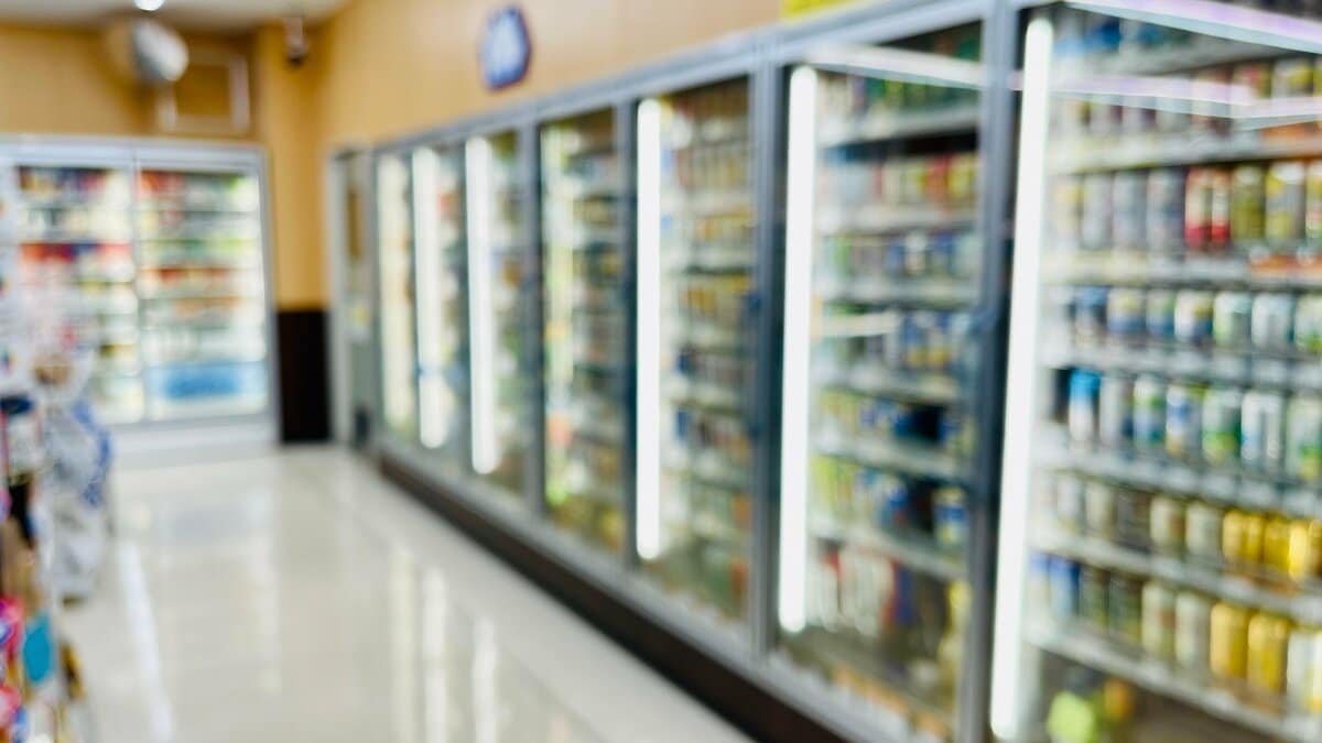 明るい照明のコンビニの店内と冷蔵ケースが並ぶ通路